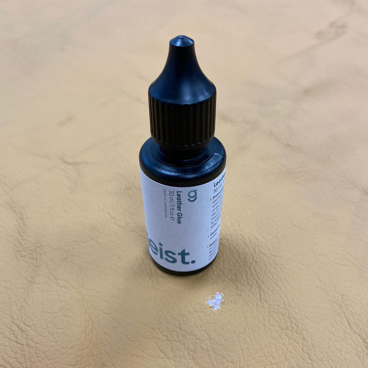Bottle labeled &#39;eist.&#39; on a beige leather surface