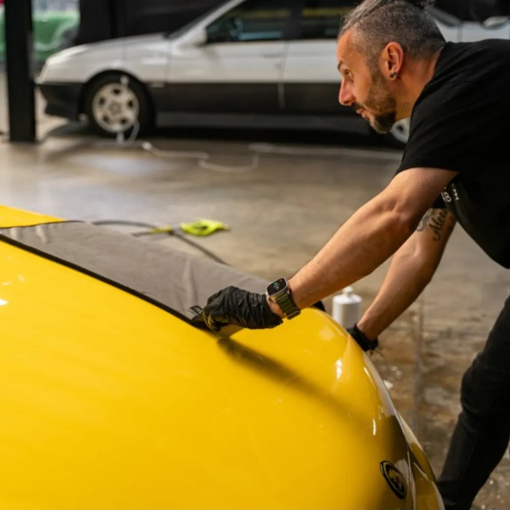 Man working on a yellow car in a garage