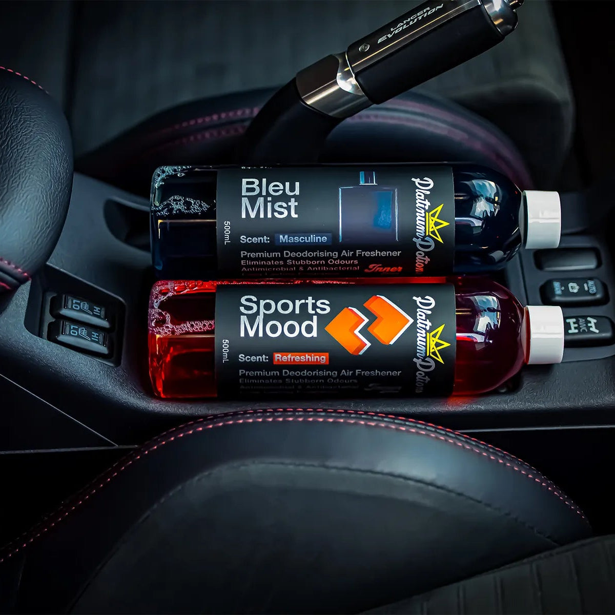 two bottles of air freshener in a car's cup holder with visible branding.