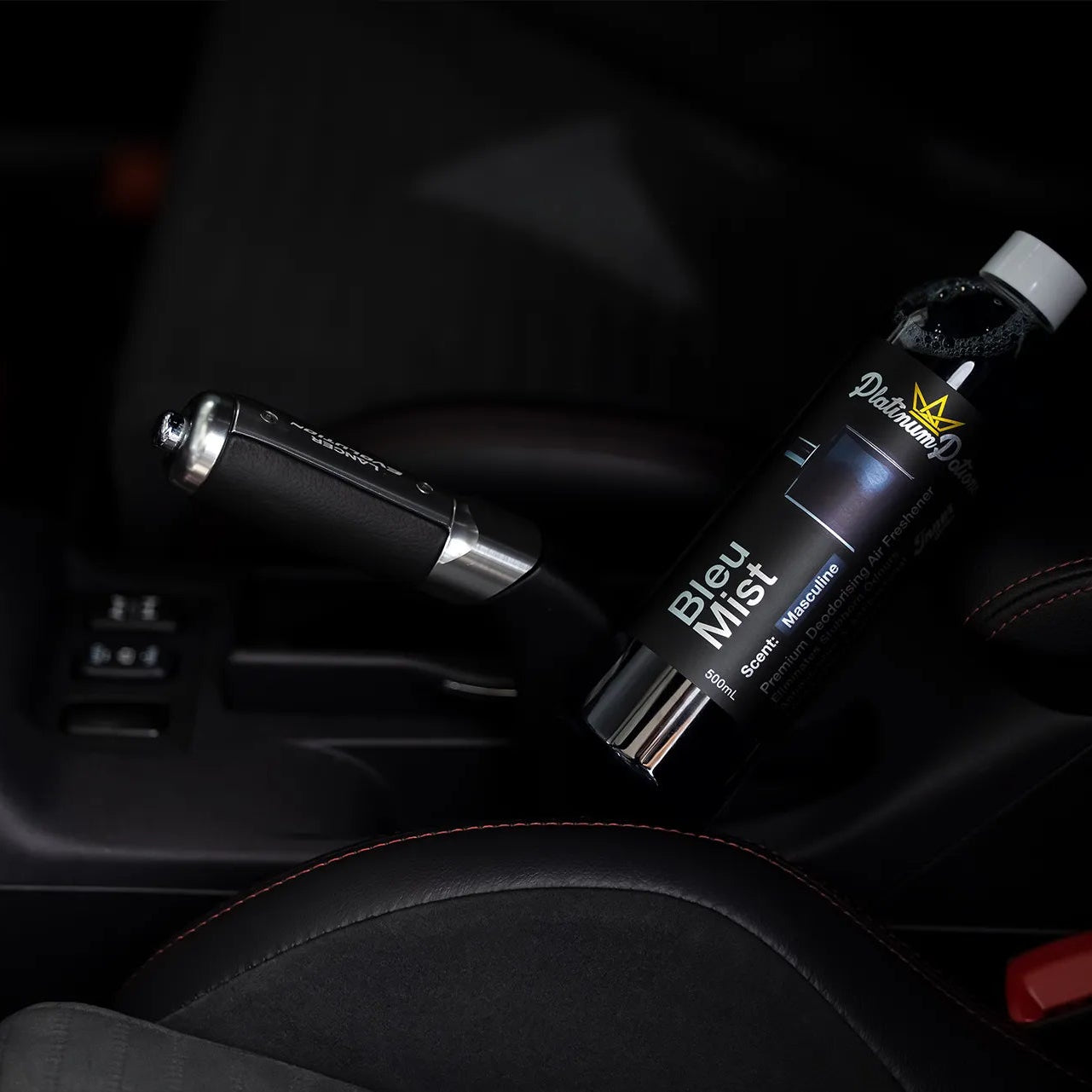 bottle of 'Bleu Mist' car air freshener on a car's dashboard.