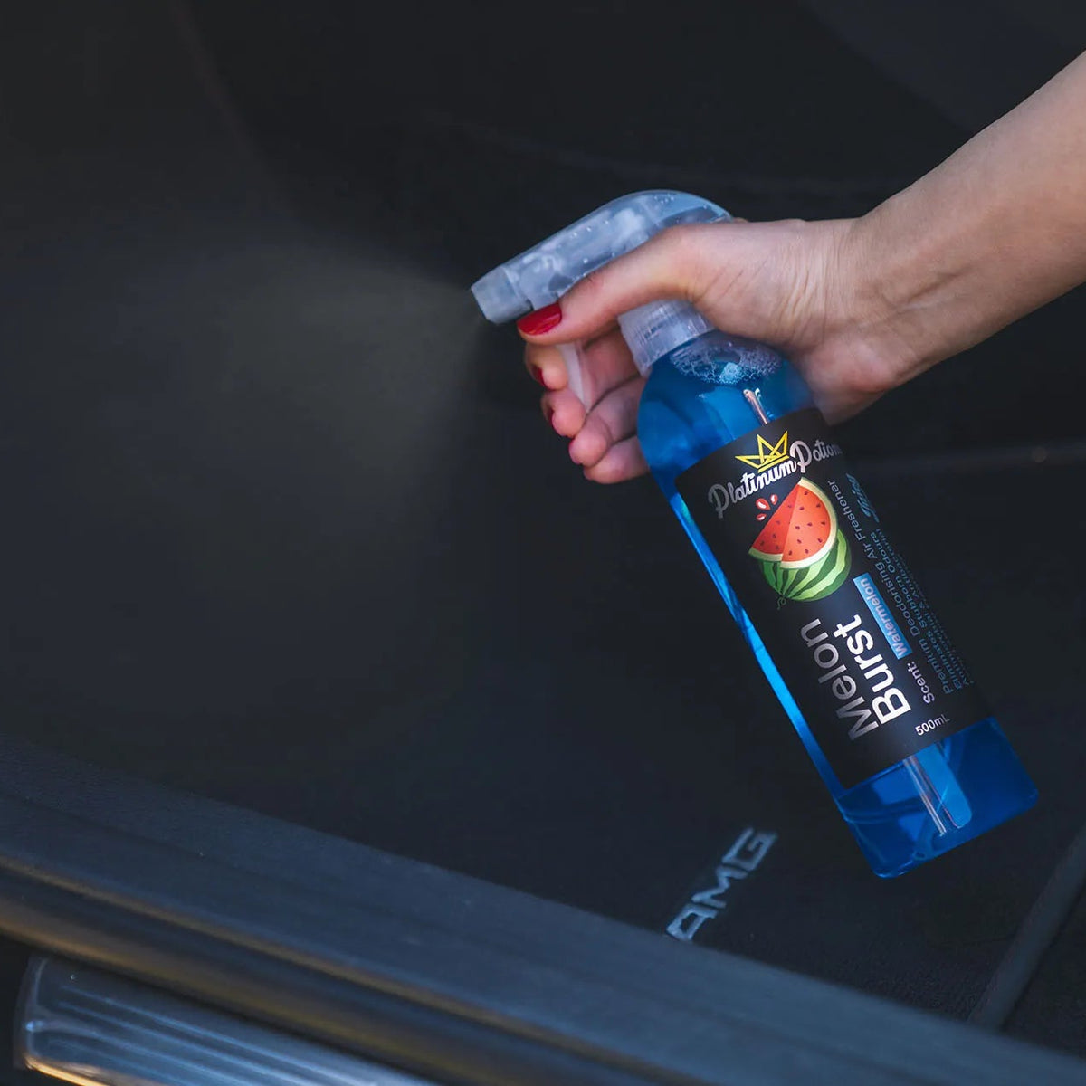 Person deodorising car interior with a spray bottle
