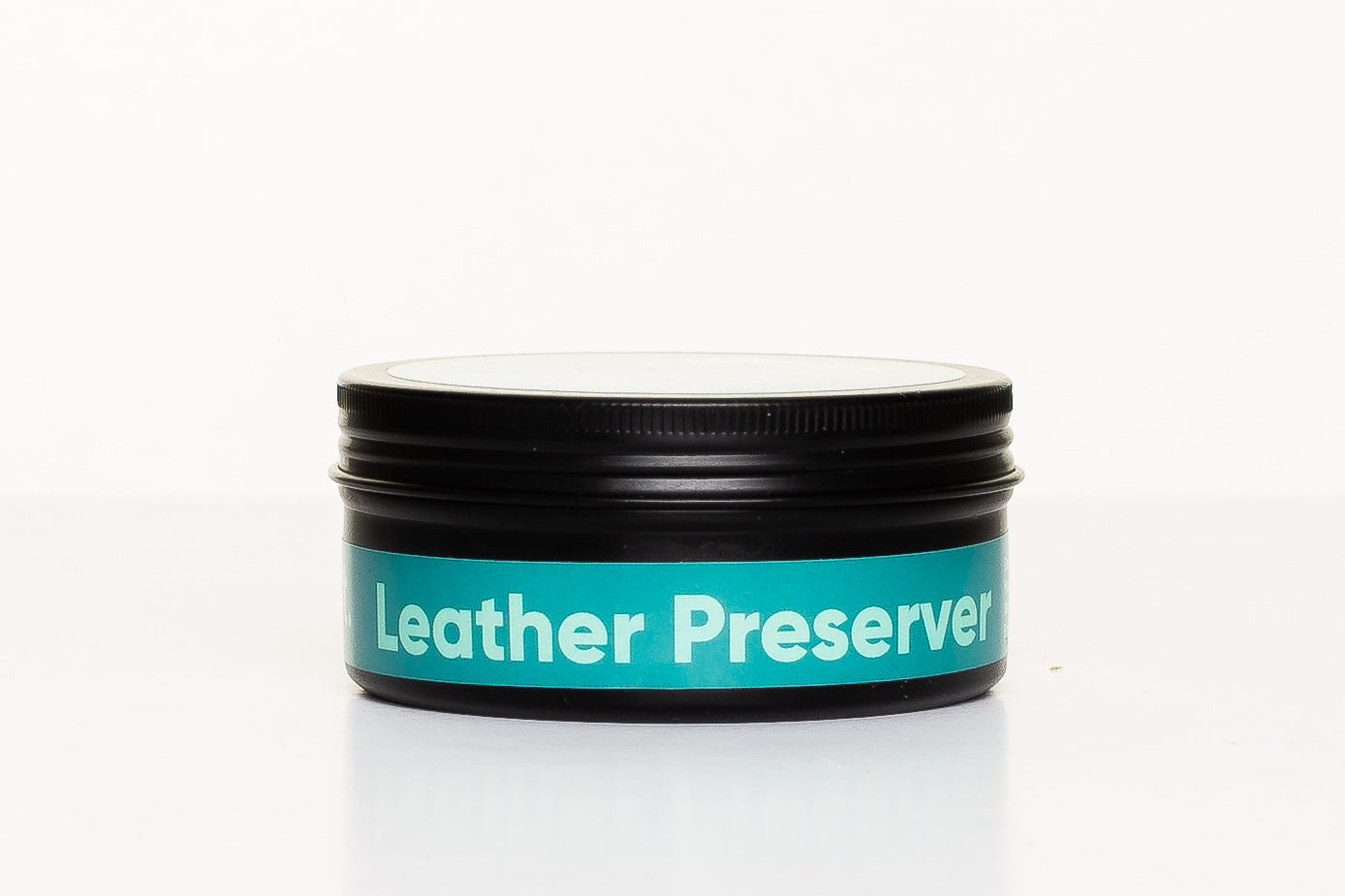 Jar of leather preserver with a white lid on a white background