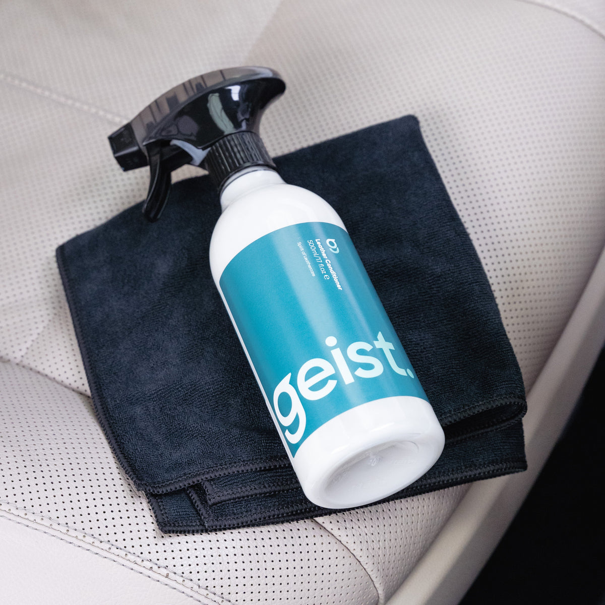 Geist cleaning spray bottle with a black towel on a car seat