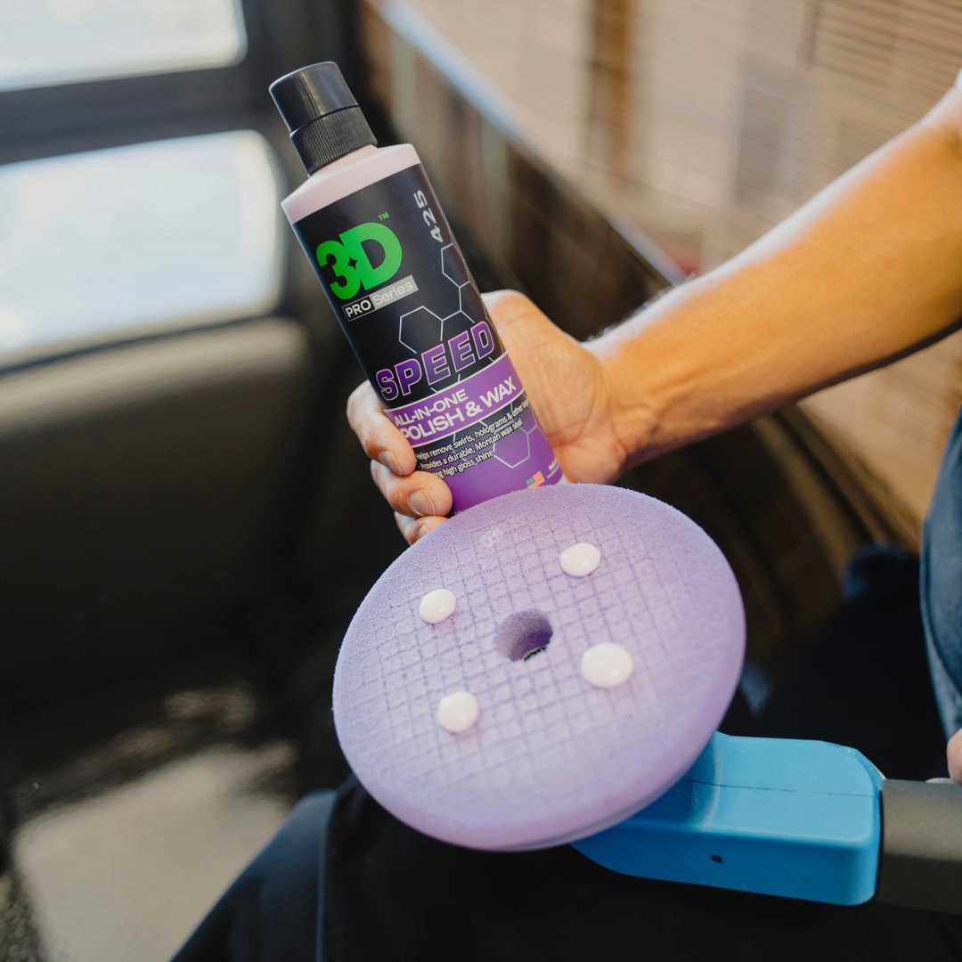 The Detail Warehouse 3D Speed all-in-one polish and wax bottle held over a purple foam polishing pad with product dots