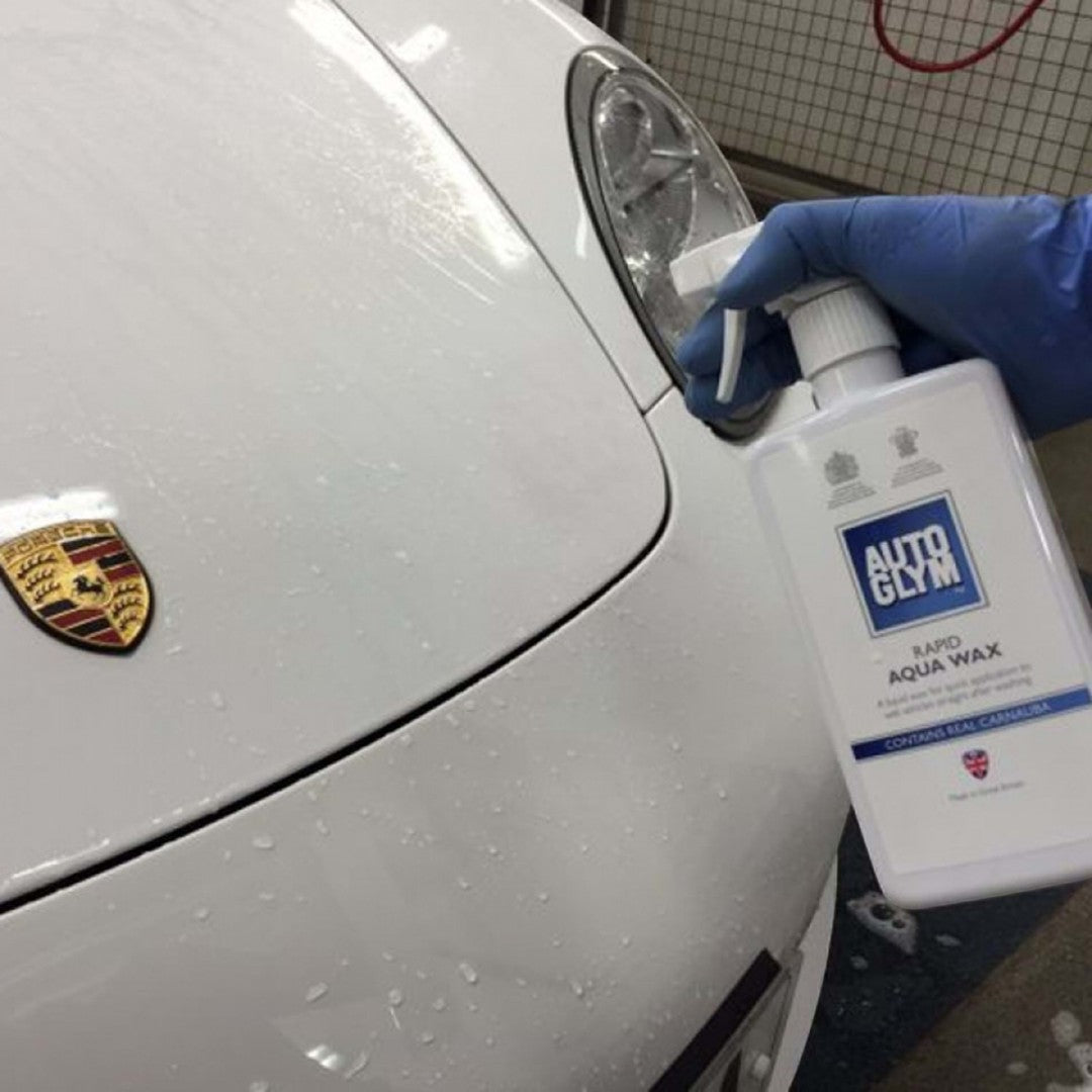 The Detail Warehouse Autoglym Rapid Aqua Wax spray bottle being applied to a wet white Porsche car hood