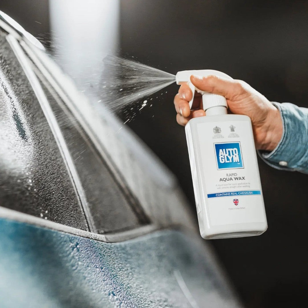 The Detail Warehouse Autoglym Rapid Aqua Wax spray bottle being applied to a wet car surface for a mirror-like shine.