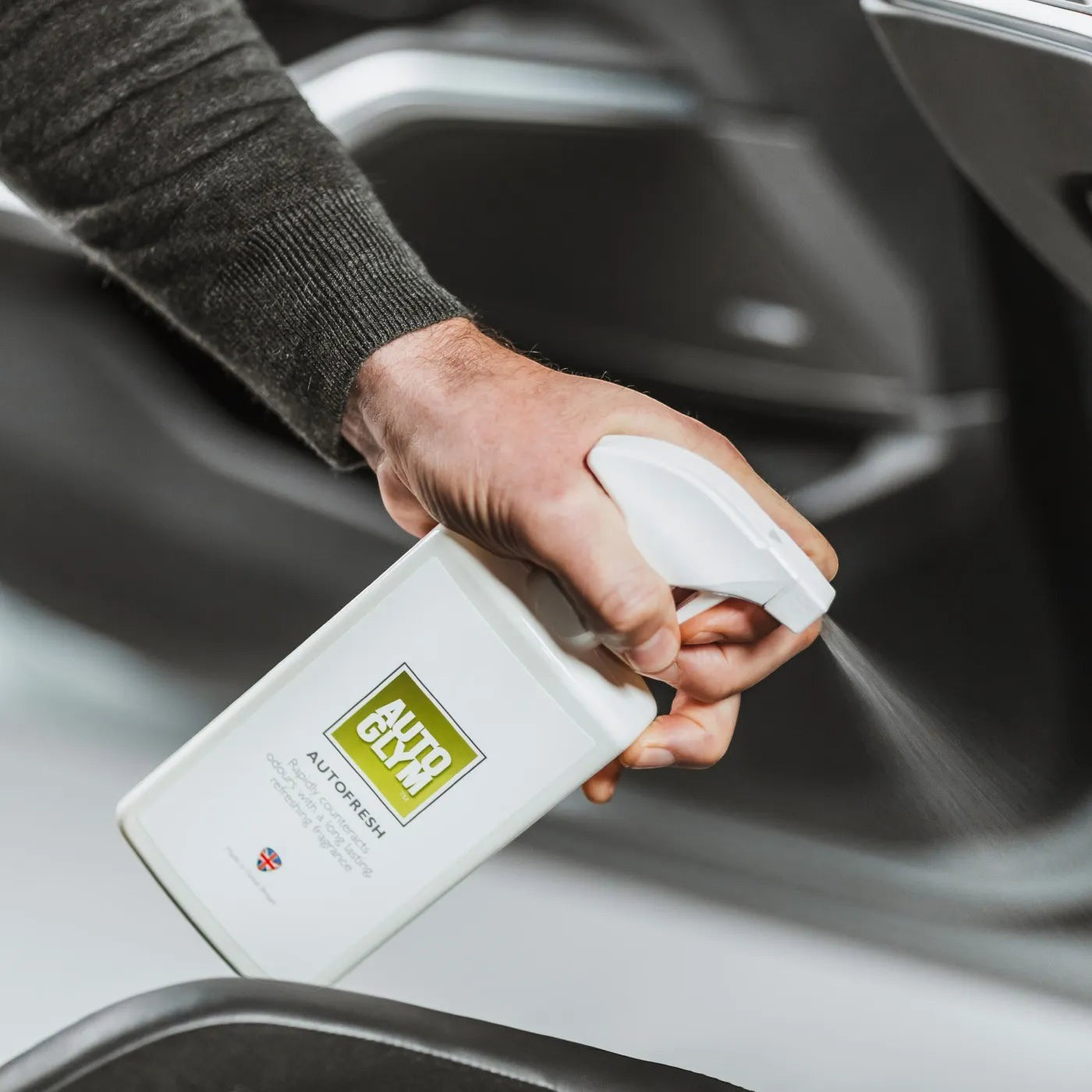 The Detail Warehouse Autoglym Autofresh spray bottle being used to freshen a car interior with a citrus fragrance.