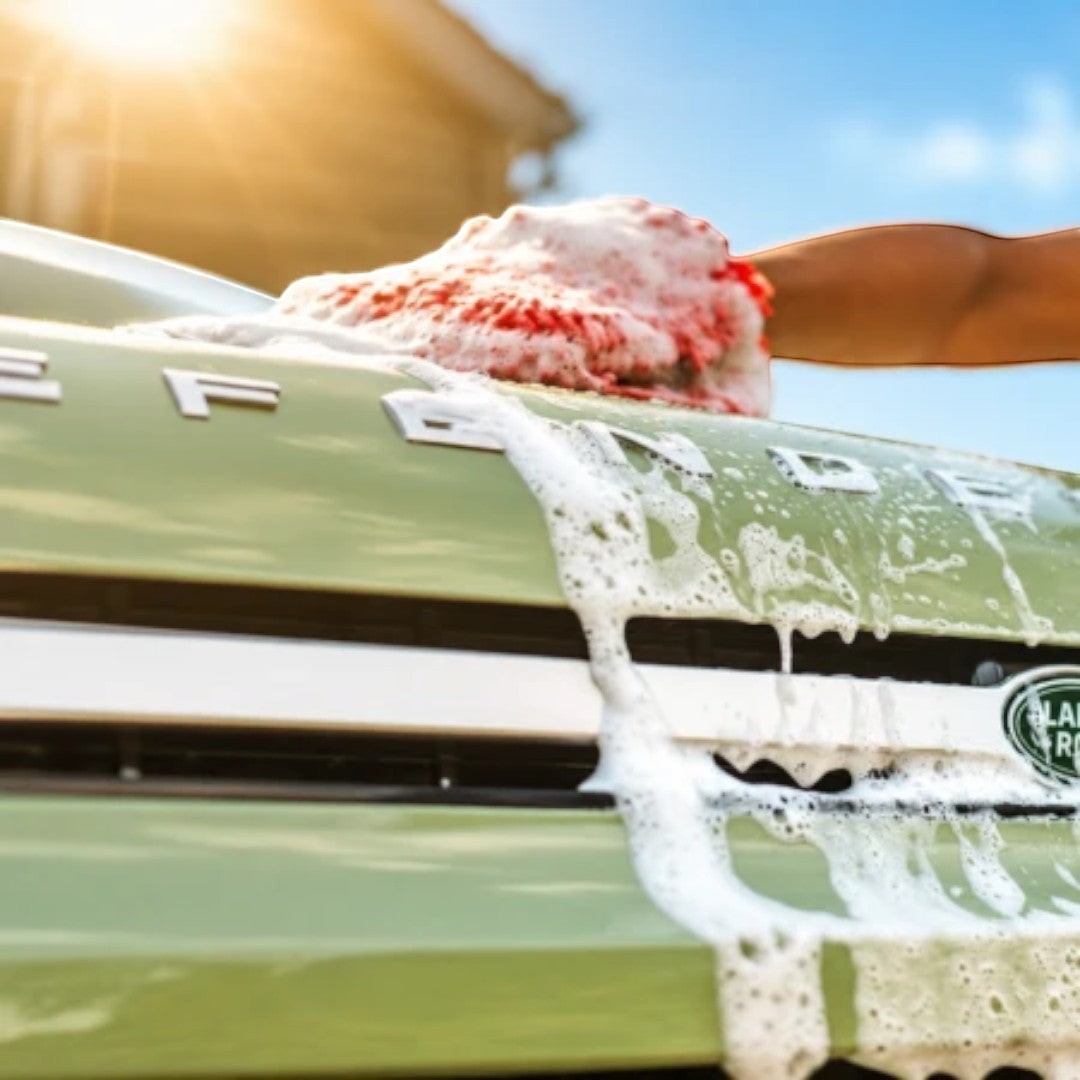 The Detail Warehouse Autoglym car shampoo creating thick foam on a green Land Rover Defender hood with a wash mitt