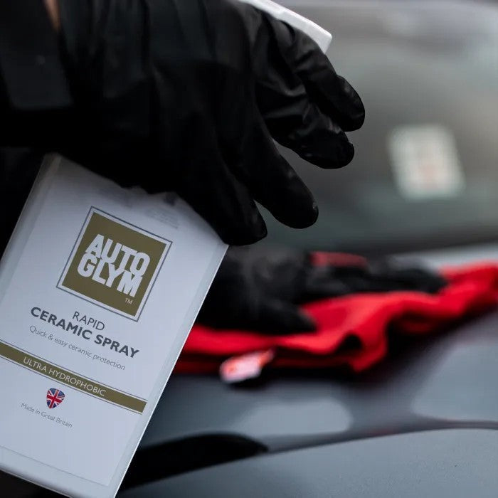 The Detail Warehouse Autoglym Rapid Ceramic Spray bottle being applied to a car hood with a red microfiber cloth