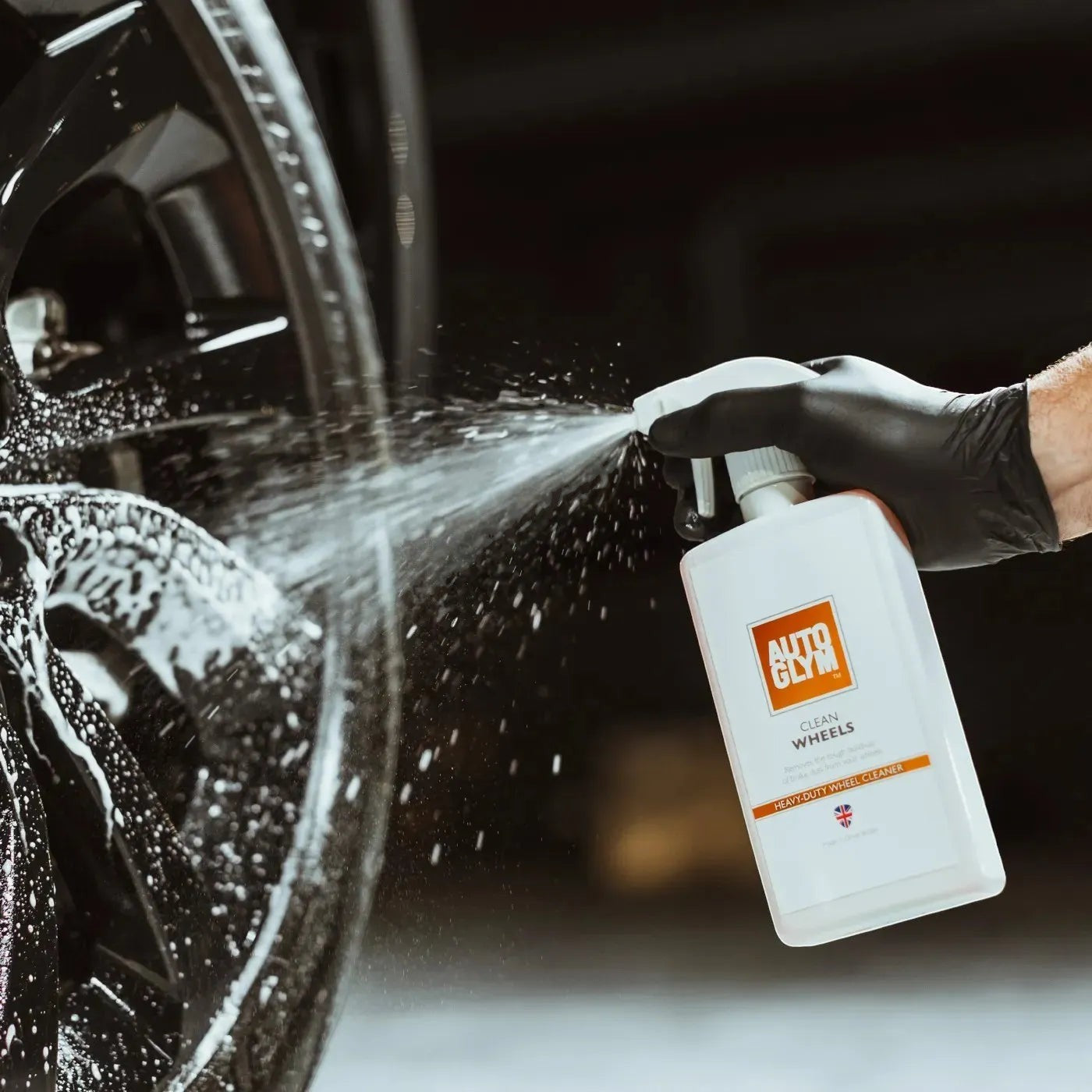 The Detail Warehouse Autoglym Clean Wheels spray bottle being used to clean a black car alloy wheel
