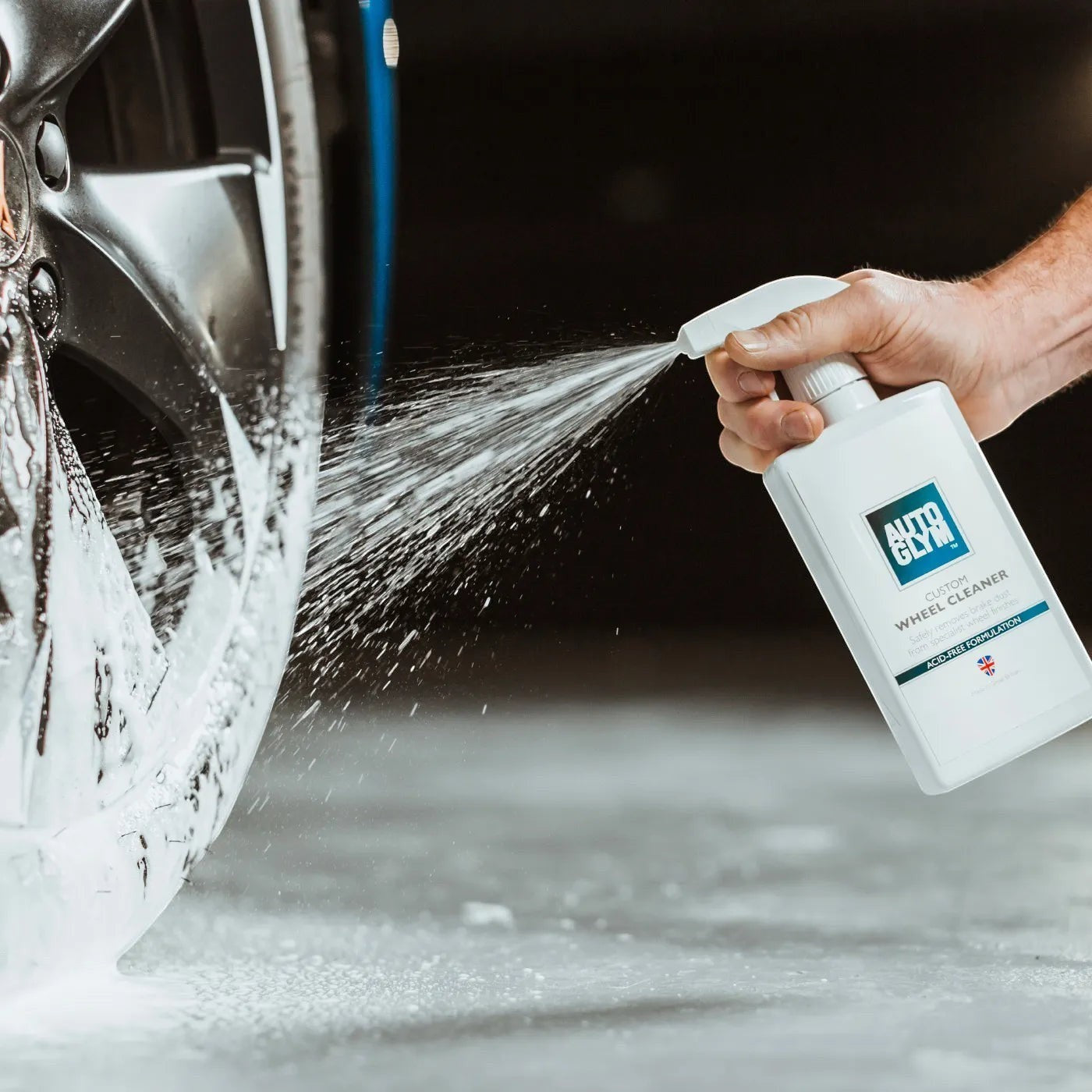 The Detail Warehouse Autoglym Custom Wheel Cleaner spray bottle being used to clean a car alloy wheel with foam