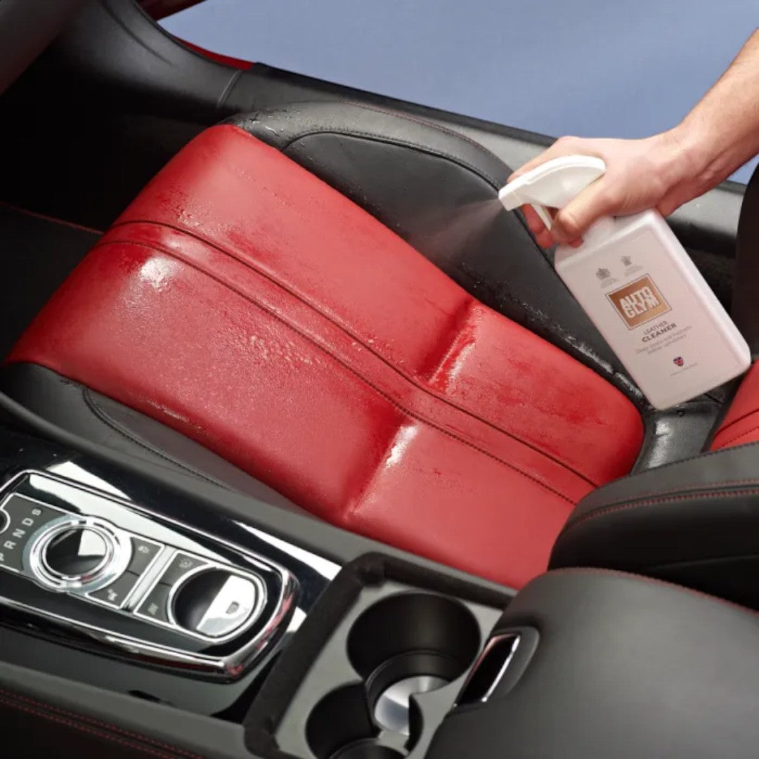 The Detail Warehouse hand spraying Autoglym Leather Cleaner onto red and black leather car upholstery
