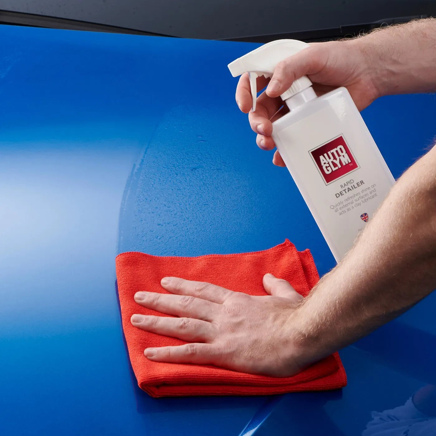 The Detail Warehouse Autoglym Rapid Detailer spray being applied to a blue car hood with a red microfiber cloth