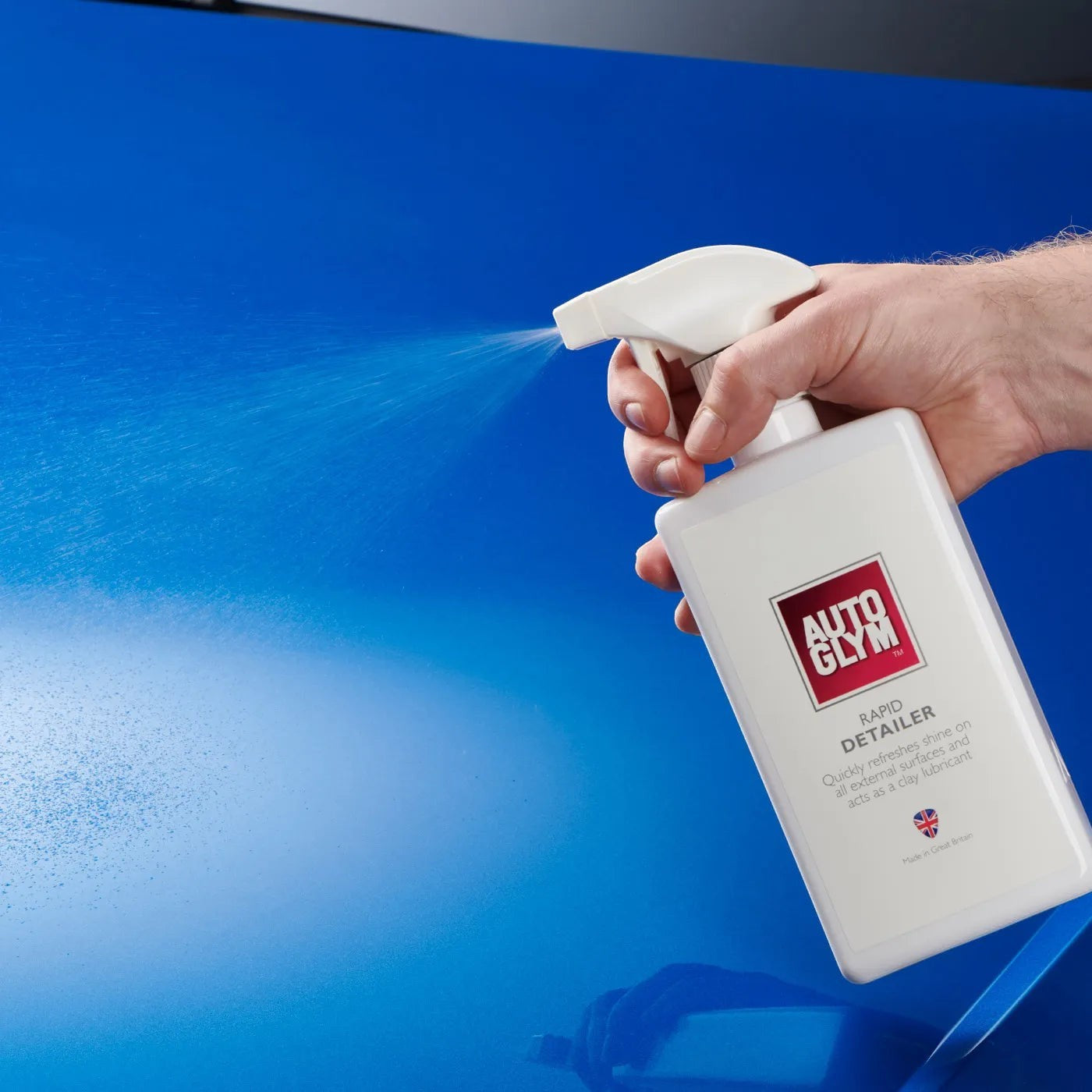 The Detail Warehouse Autoglym Rapid Detailer spray bottle being used to mist a glossy blue car paint surface
