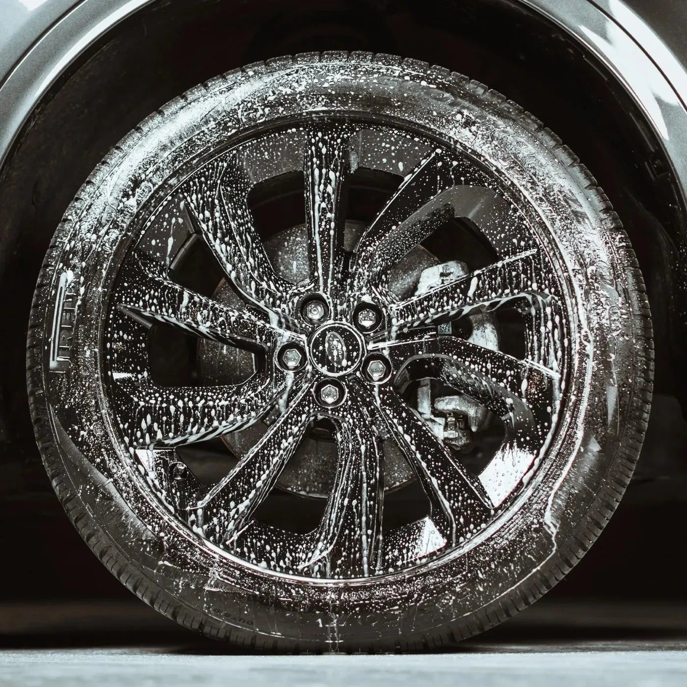 The Detail Warehouse Autoglym Clean Wheels spray applied to a black alloy car wheel, showing foam dissolving brake dust.