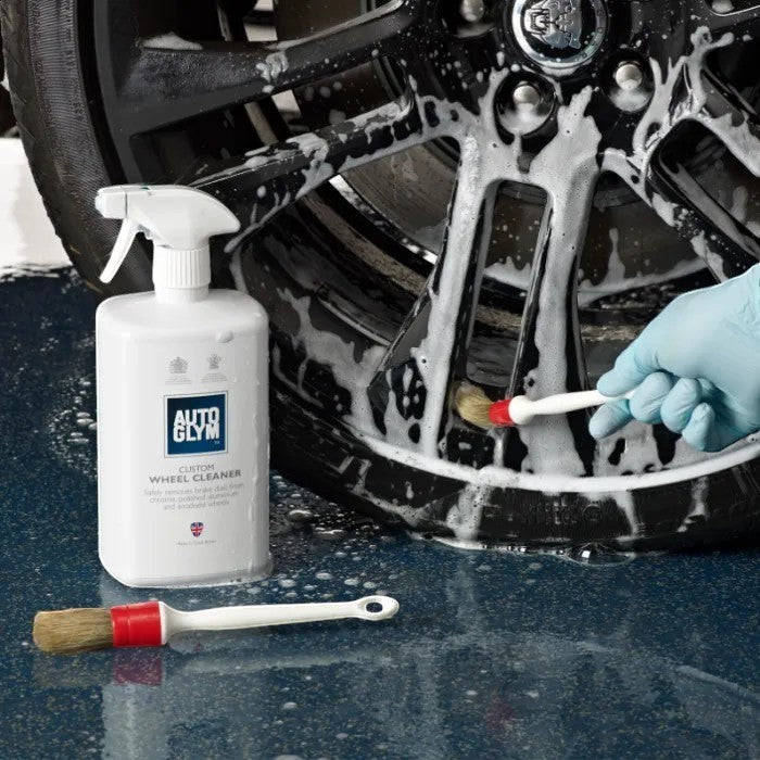 The Detail Warehouse Autoglym Custom Wheel Cleaner spray bottle being used with a brush to clean a car alloy wheel