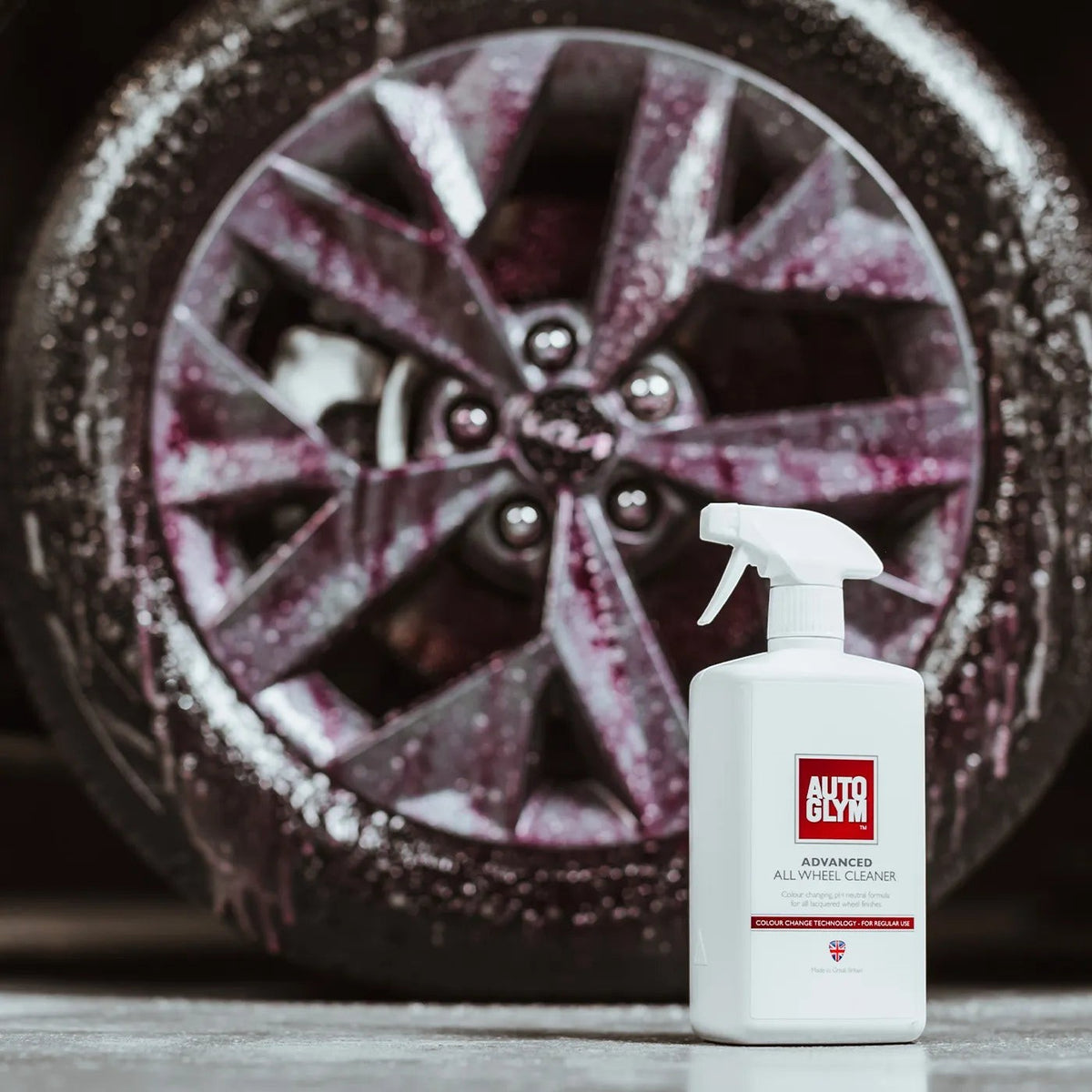 The Detail Warehouse Autoglym Advanced Wheel Cleaner bottle in front of a car wheel covered in purple cleaning foam
