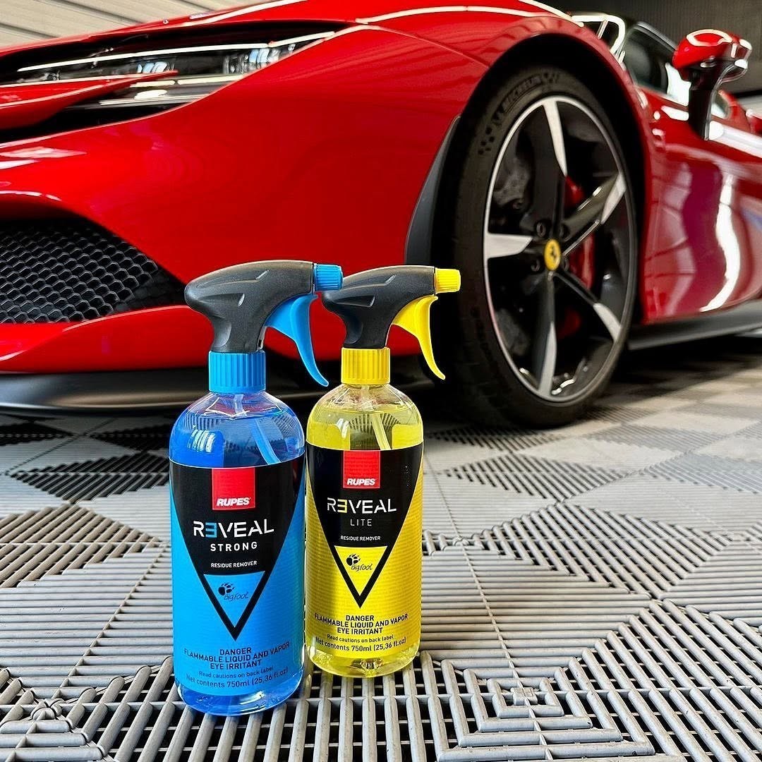 The Detail Warehouse Rupes Reveal Strong and Reveal Lite residue remover spray bottles in front of a red sports car