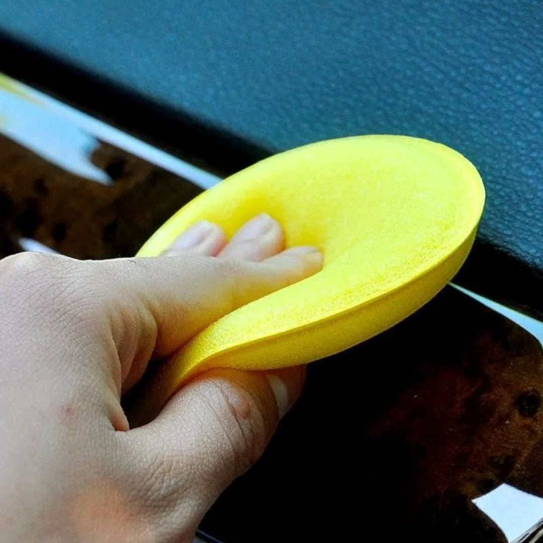The Detail Warehouse bright yellow foam applicator pad being held and squeezed to show flexibility and texture