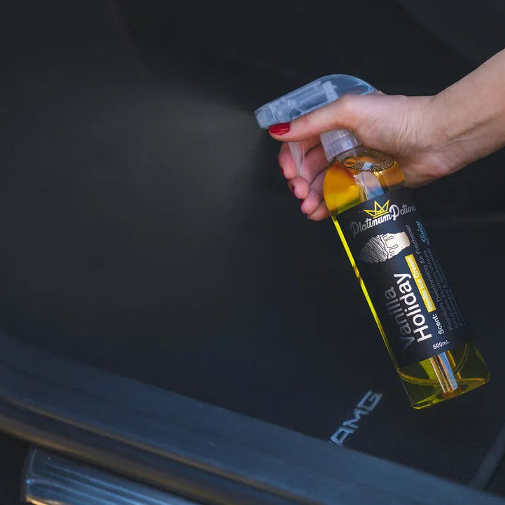 Person holding a bottle of Repelant near a car's open trunk